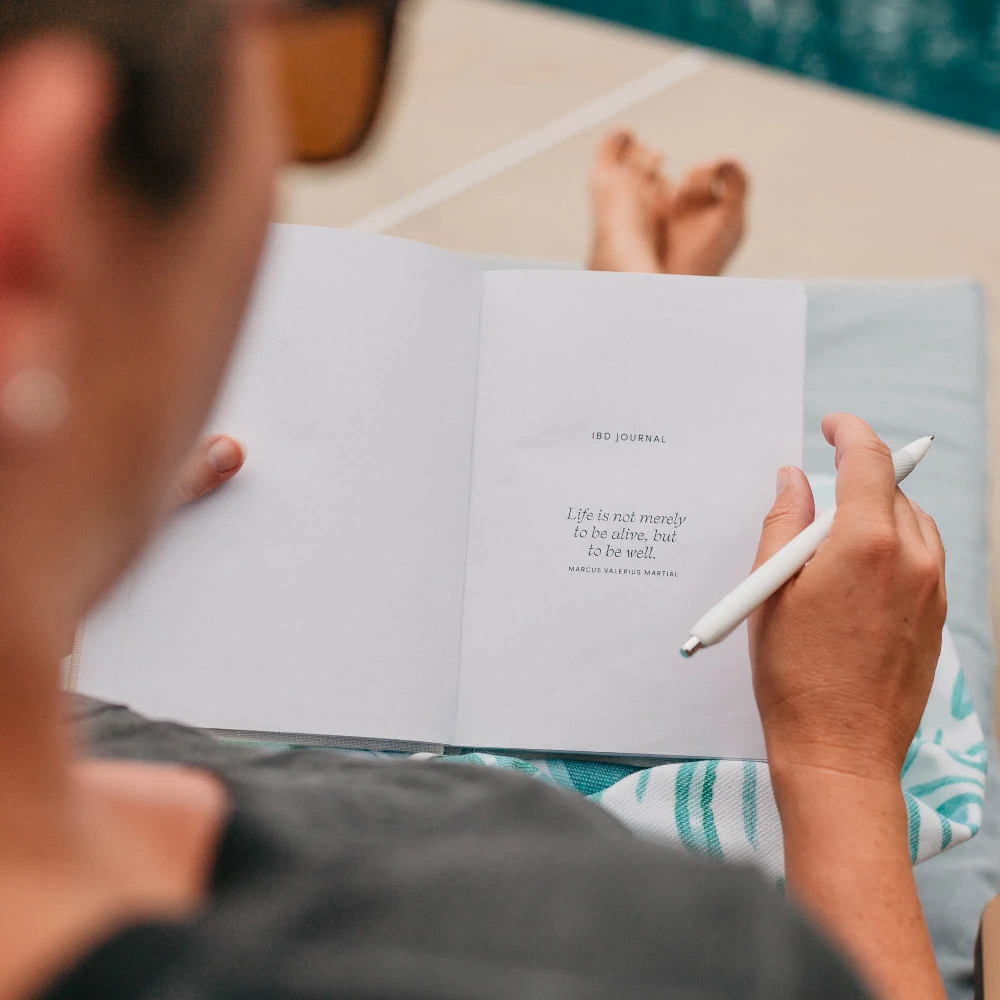 Person holding open a white journal with an inspirational quote about life while holding a pen.