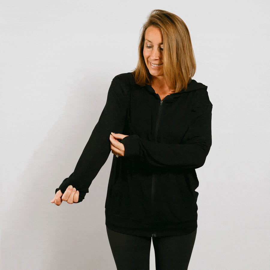 Woman wearing black bamboo IV zip hoodie with front zipper, demonstrating adaptive arm access feature.