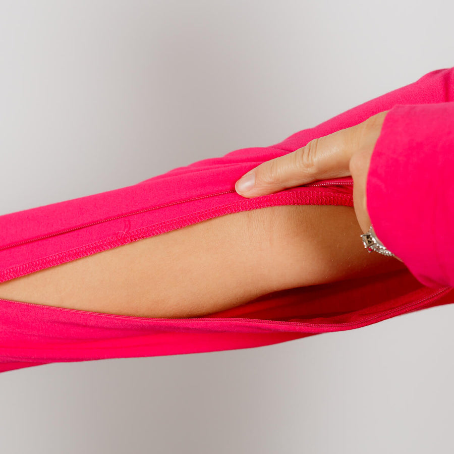 Woman wearing hot pink IV zip hoodie with left arm zipper access feature visible.