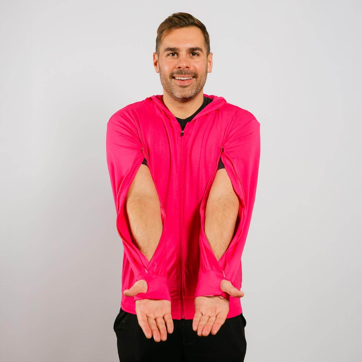 Man wearing a bright pink jacket with cut-out sleeves on a plain background | Model is 5'8" 165lbs wearing size M