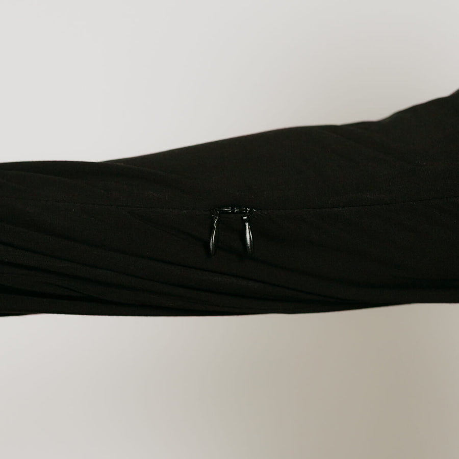An arm showing the sleeve of a black zip hoodie showing two zippers on a seam on the inner arm.