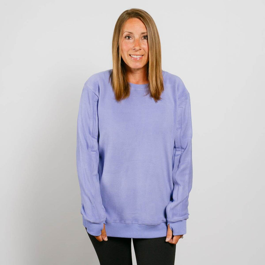 Woman wearing a light purple crewneck sweatshirt with black pants against a white background.