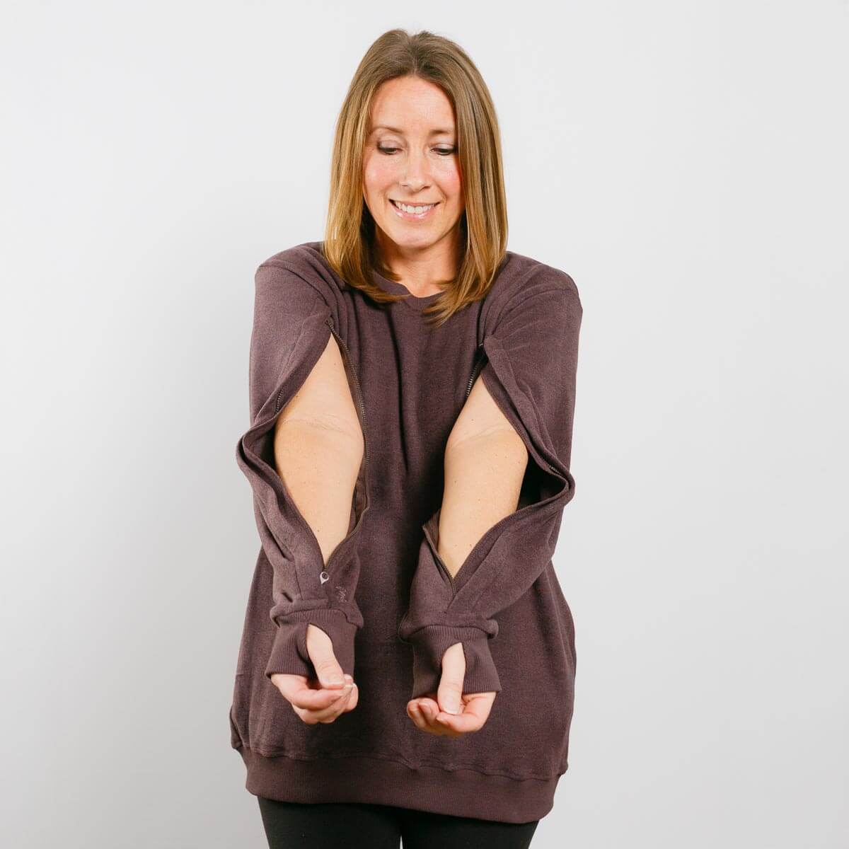 Woman wearing burgundy IV crewneck with open side zippers for medical access, front view.