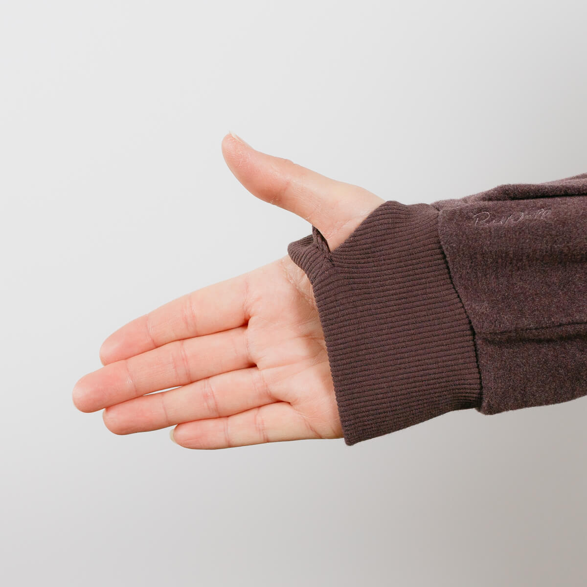 Person wearing brown IV crewneck with arm extended, showing accessible sleeve design detail.