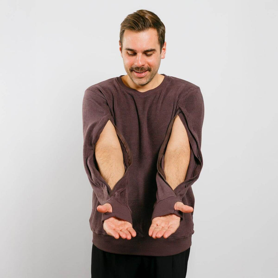 Man wearing a brown sweatshirt with cut-out design on a plain background