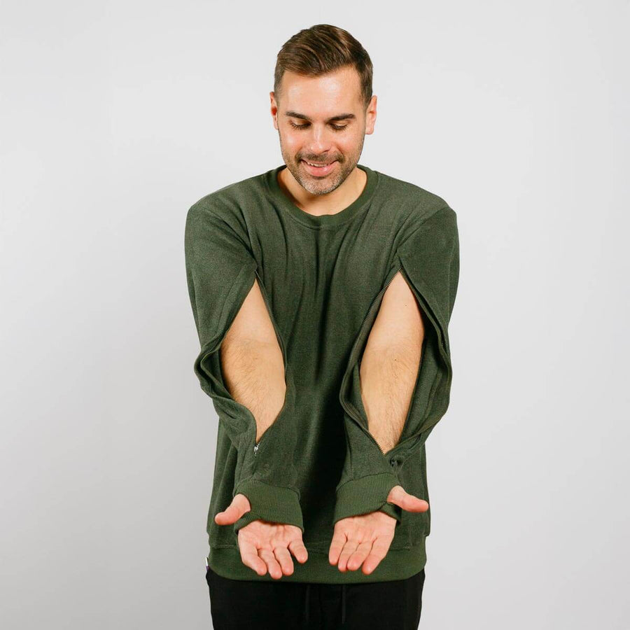 Man wearing a green long-sleeve shirt with cut-out designs on a plain background