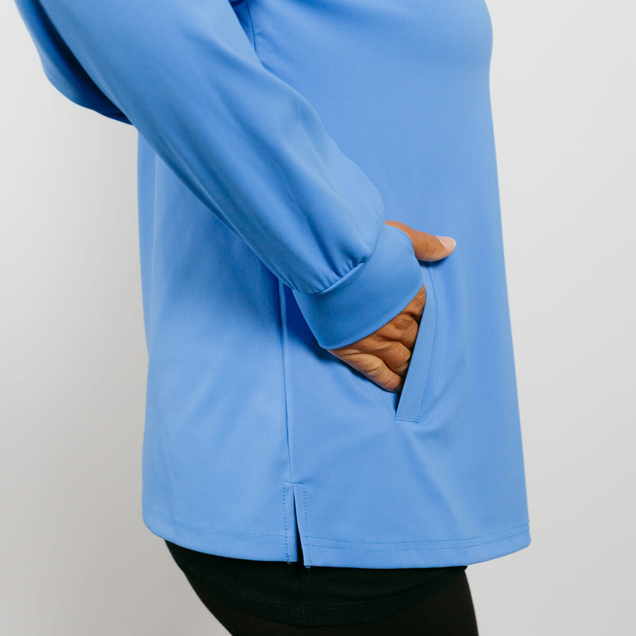 Blue quarter zip pullover with brown corduroy-lined pocket and person's hand visible.