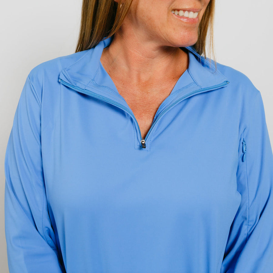 Woman wearing a light blue quarter-zip pullover with long sleeves and a collar.
