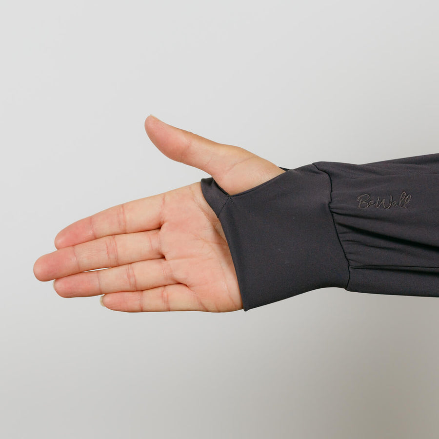 Person's open hand wearing a charcoal gray quarter zip pullover with thumb extended upward.