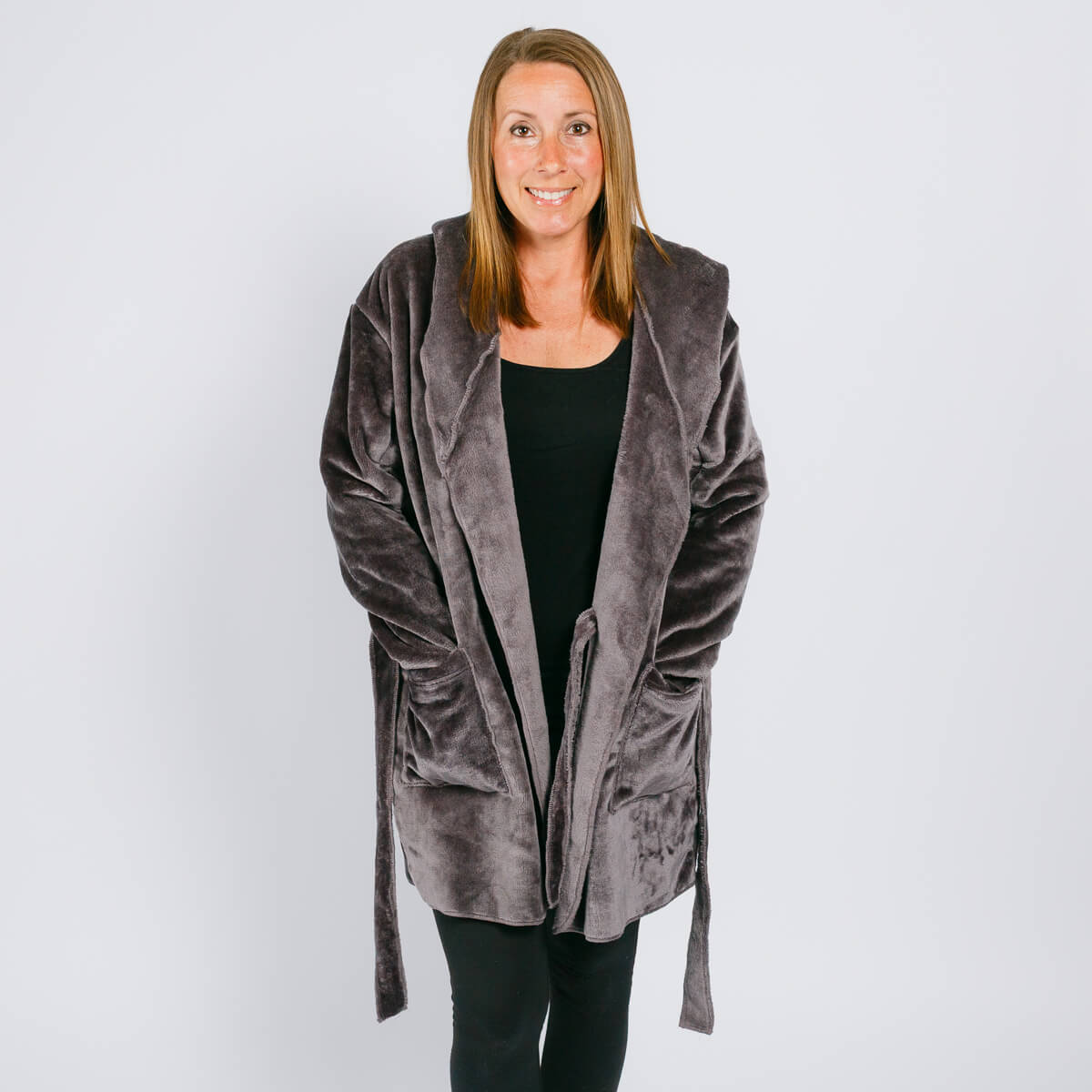 Woman wearing a gray velvet hooded robe over a black shirt against a white background.