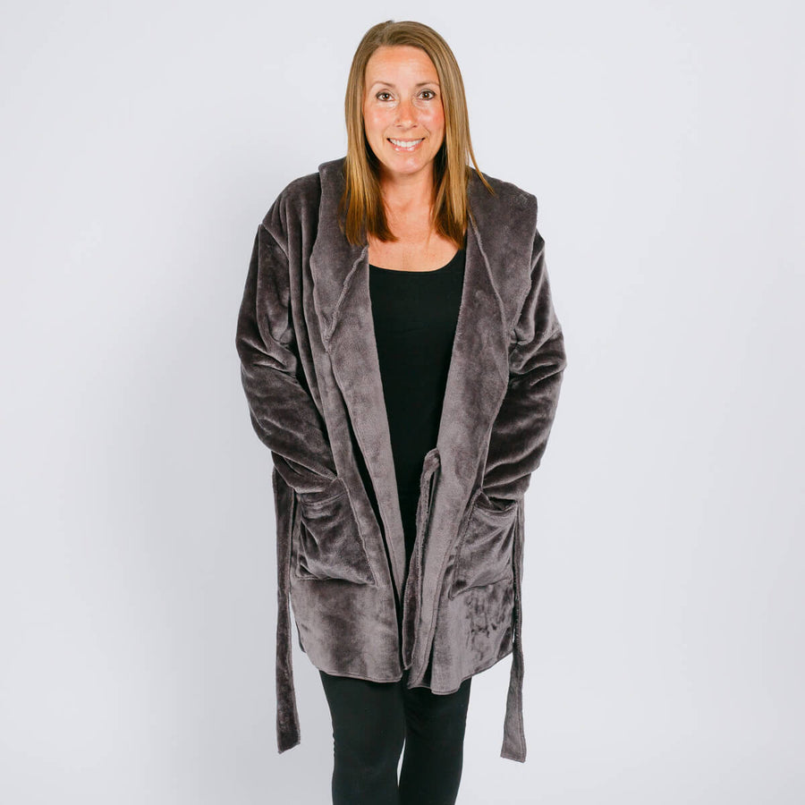Woman wearing a gray velvet hooded robe over a black shirt against a white background.