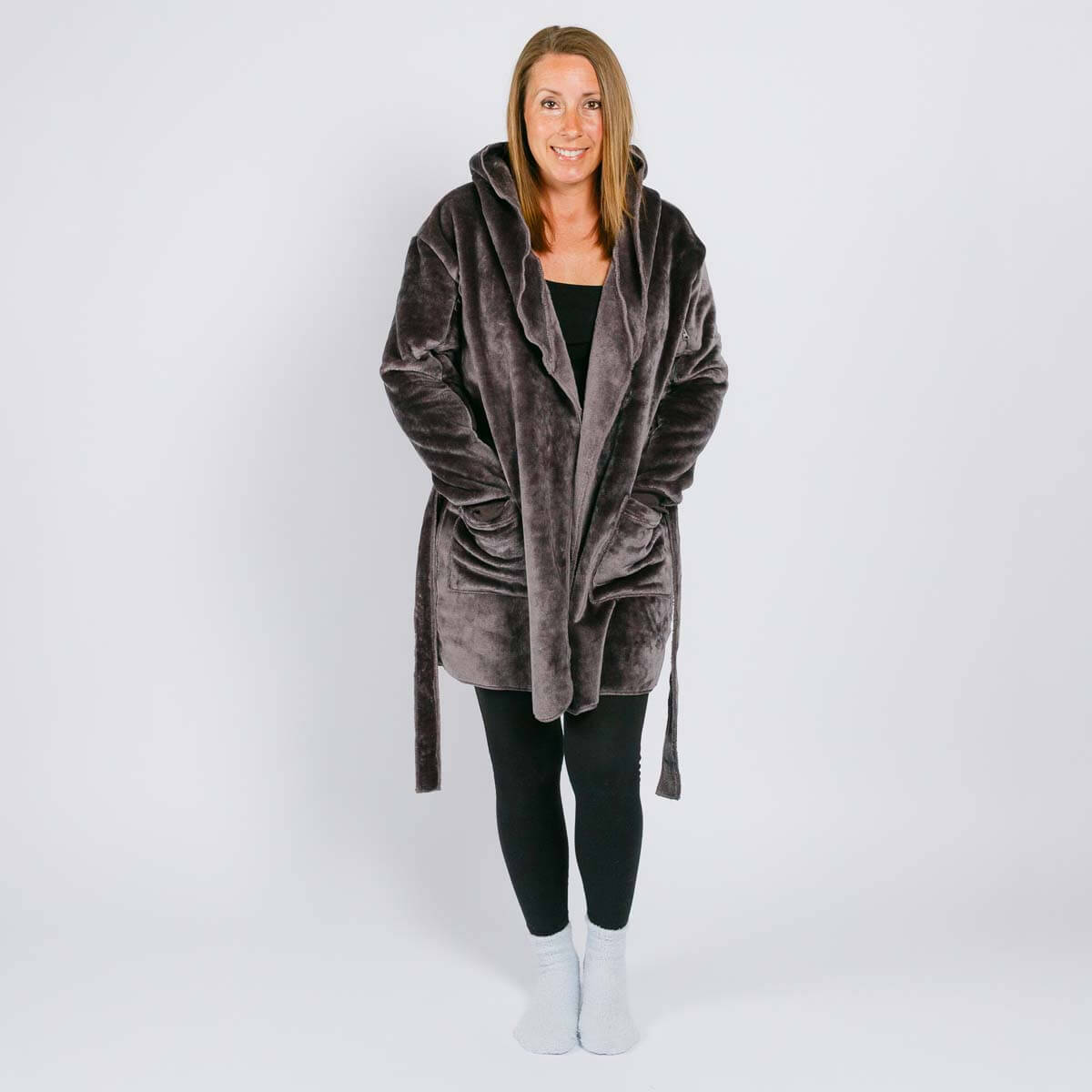Woman wearing a gray velvet hooded robe over black clothing with white socks.