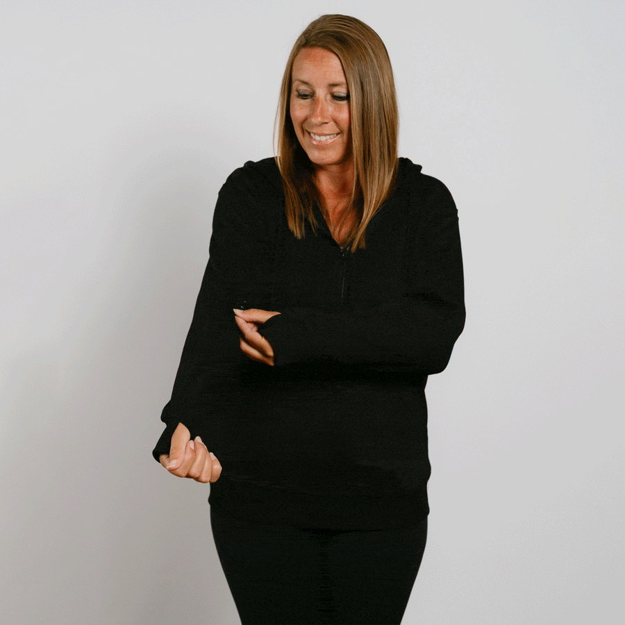 Woman wearing a black zip-up hoodie with her eyes downward and arms crossed.