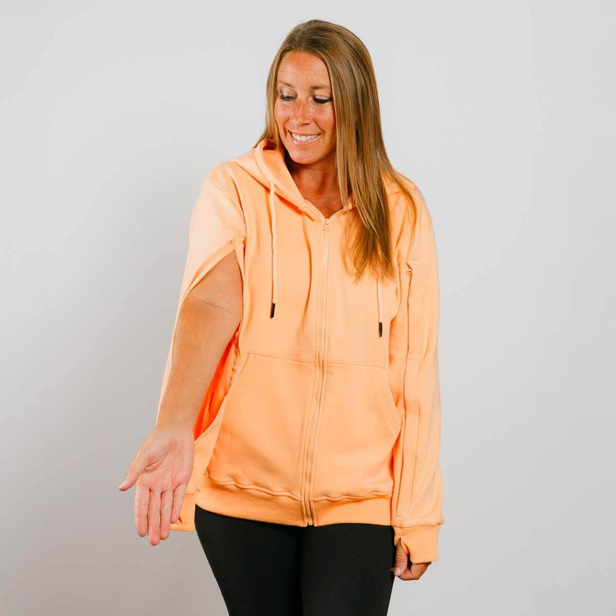 Woman wearing peach IV zip hoodie with side zipper access, front view.