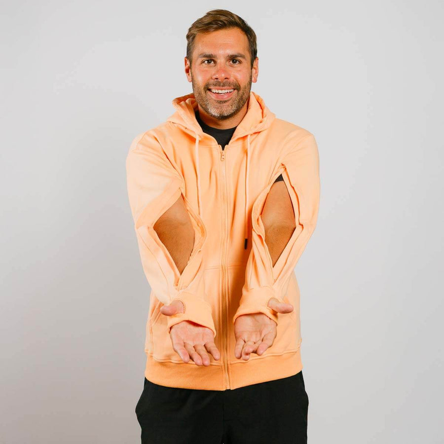 Man wearing a peach-colored hoodie with mesh panels on a gray