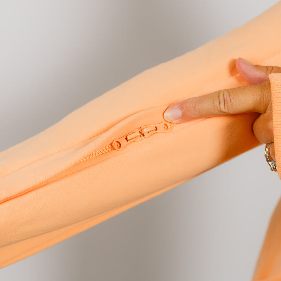Close-up of peach IV zip hoodie sleeve showing zipper opening for arm access during treatment.