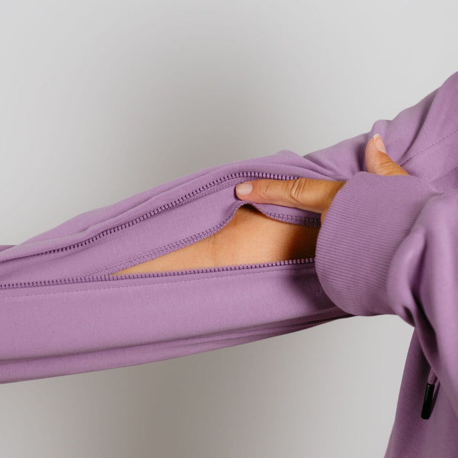 Person's hand opening a purple zip hoodie to show the interior lining and zipper detail.