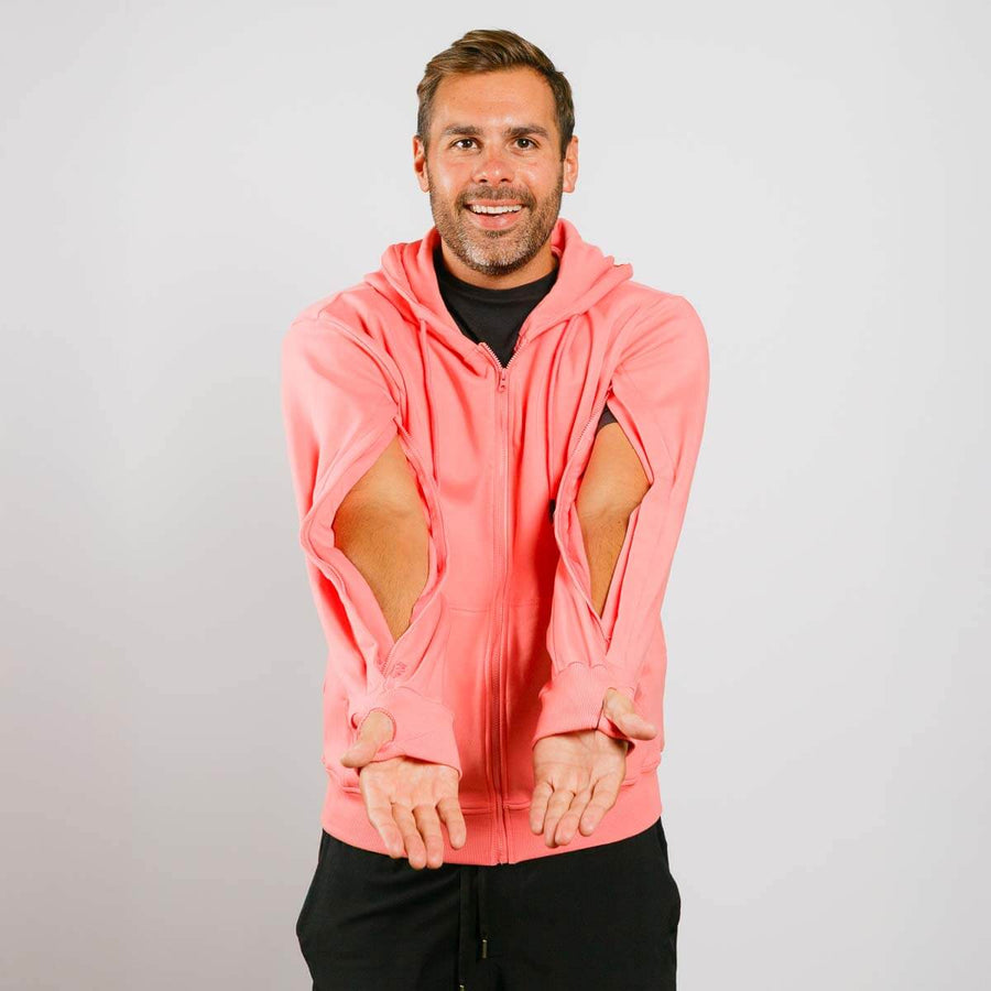 Man wearing a pink hoodie with cut-out sleeves on a plain background