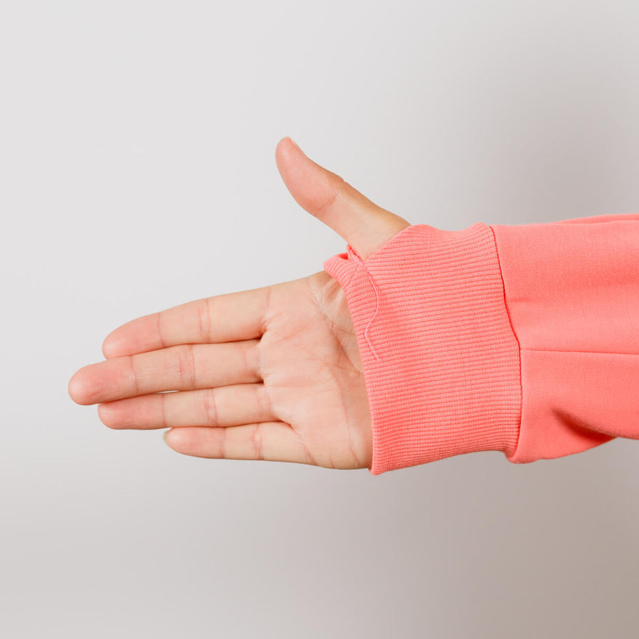Person wearing coral IV zip hoodie with left sleeve zipper access detail visible.
