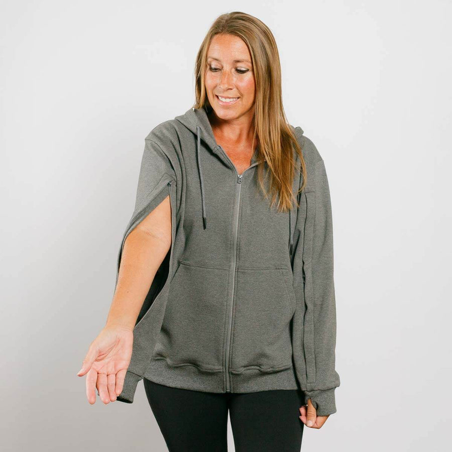 Woman wearing gray zip hoodie with left arm zipper access feature visible during treatment.