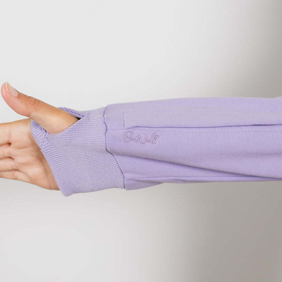 Woman wearing lavender IV zip hoodie with left arm zipper access open during treatment.