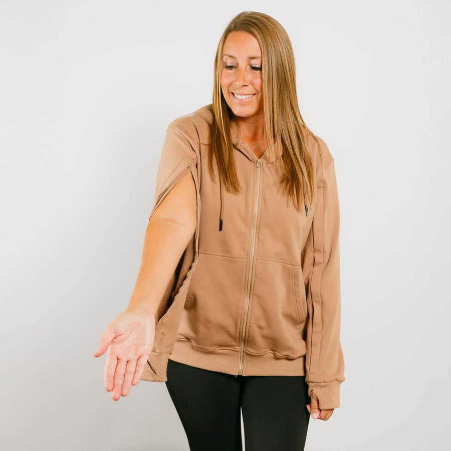 Woman wearing tan IV zip hoodie with front zipper, smiling in front view.