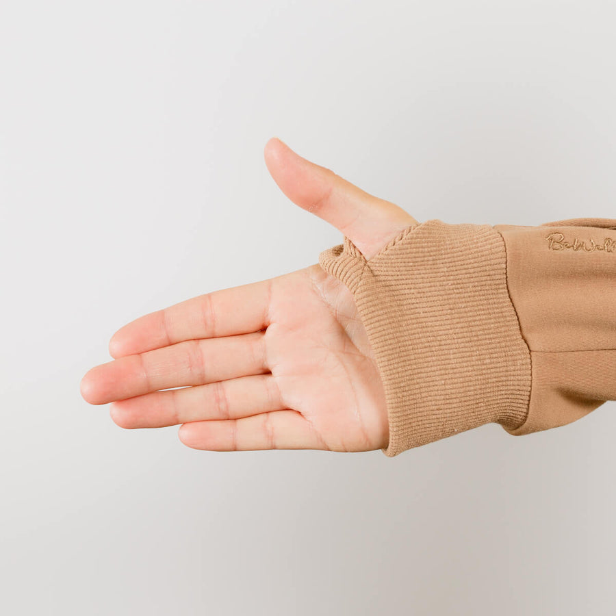 Close-up of beige IV zip hoodie sleeve showing wrist zipper access detail on person's arm.