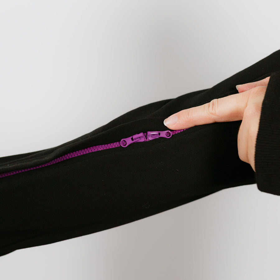 Person wearing black IV zip hoodie with purple arm zipper access feature visible.