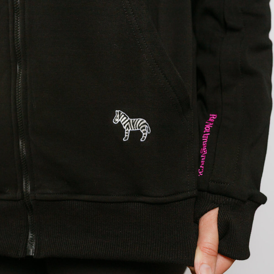 Close-up of black IV zip hoodie showing zebra emblem and purple text detail on sleeve.