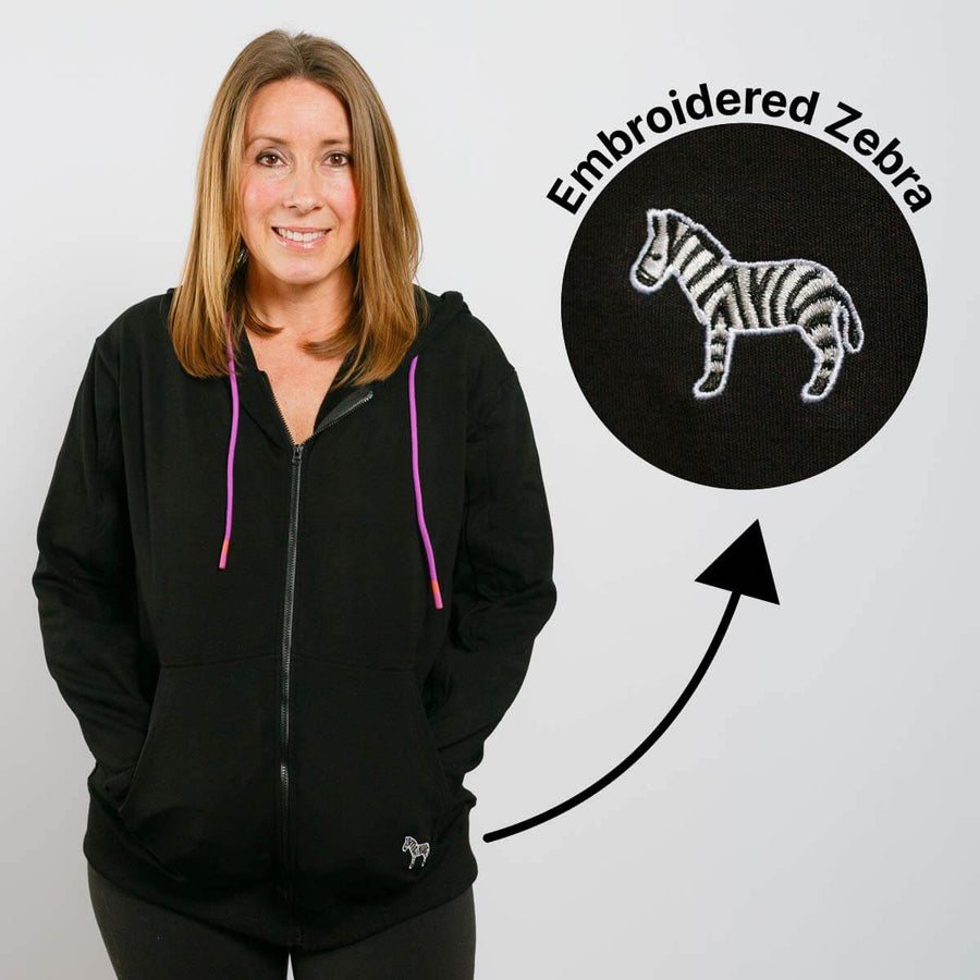 Woman wearing black IV zip hoodie with purple drawstrings and embroidered zebra detail.