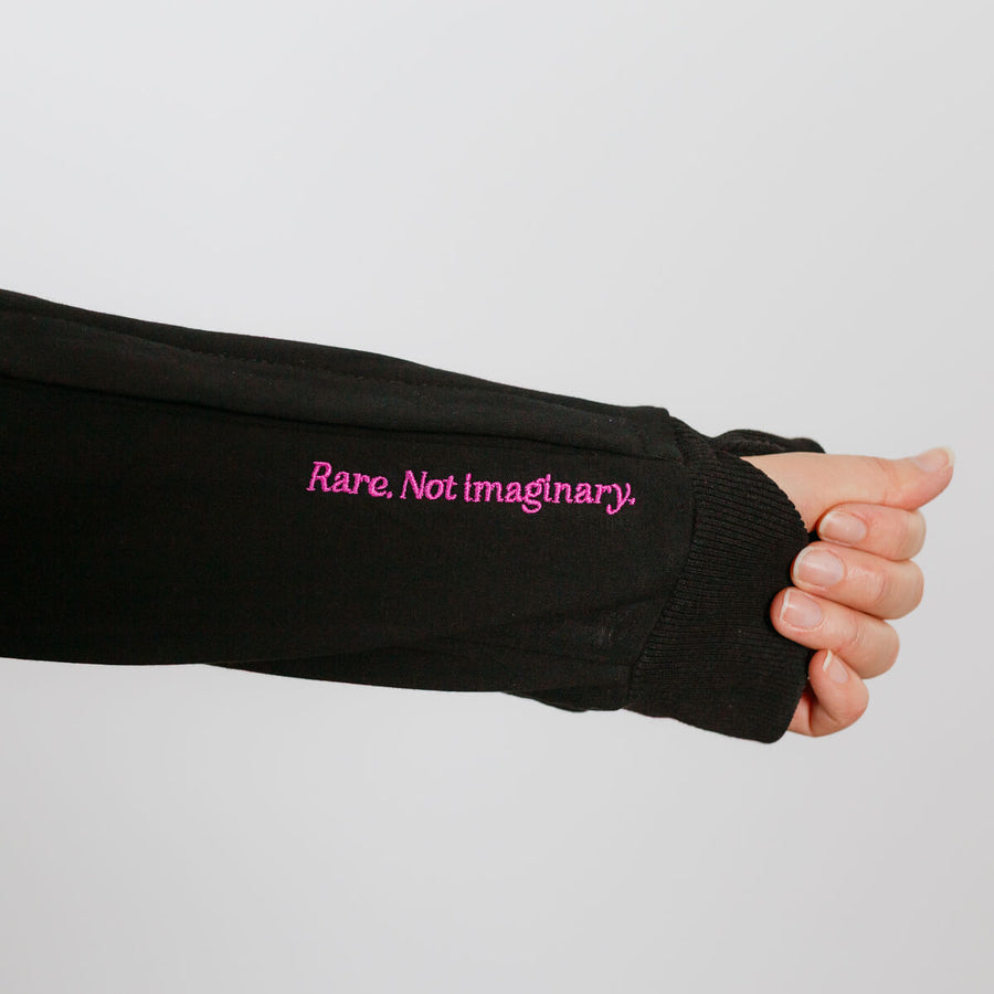 Person wearing black IV zip hoodie with left sleeve zipper access detail visible on arm.