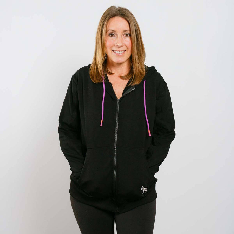 Woman wearing black IV zip hoodie with pink drawstring accents, front view.