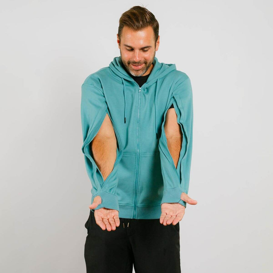 Man wearing turquoise zip-up hoodie with large cutout holes on both sides of torso.