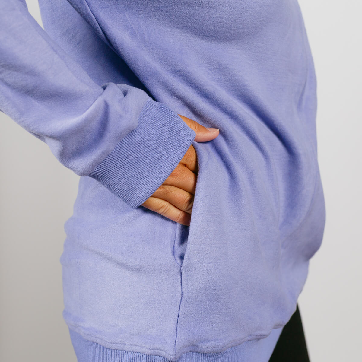 Person wearing light purple crewneck sweatshirt with hand visible through accessible side opening.