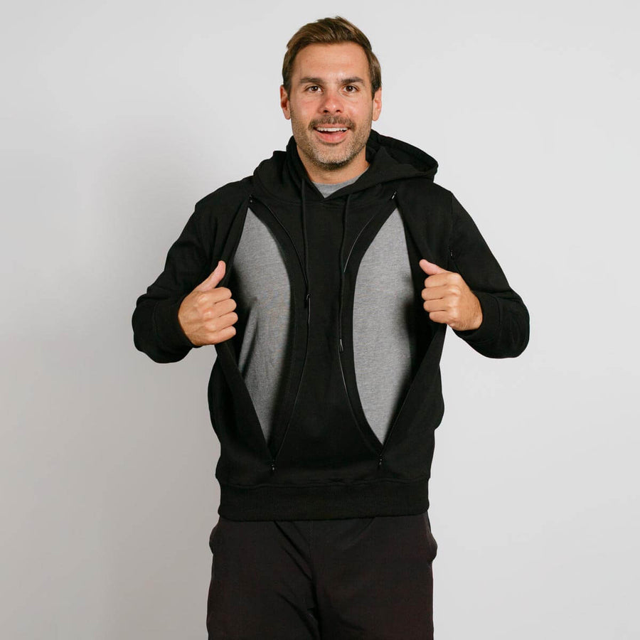 Man wearing black zip-up hoodie over gray shirt, giving double thumbs up against white background.