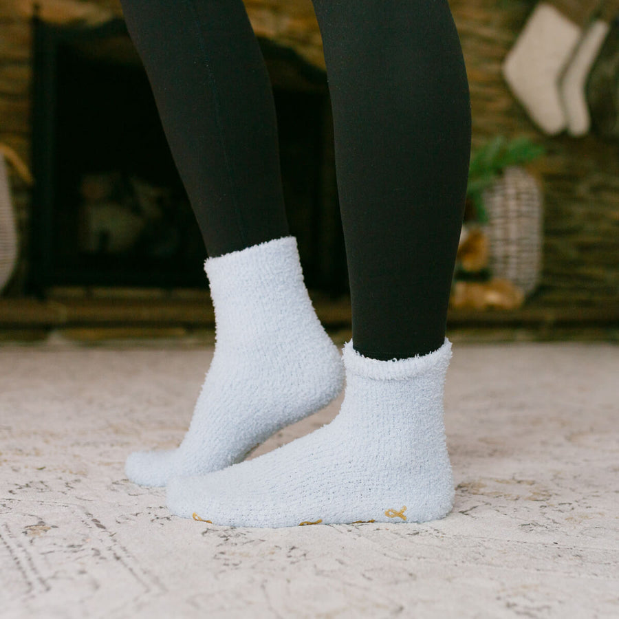 Person wearing white rest day socks with black leggings, standing outdoors on pavement.