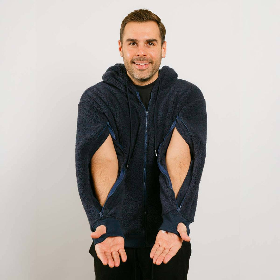 Man wearing a dark blue hoodie with cut-out arm designs on a light gray background