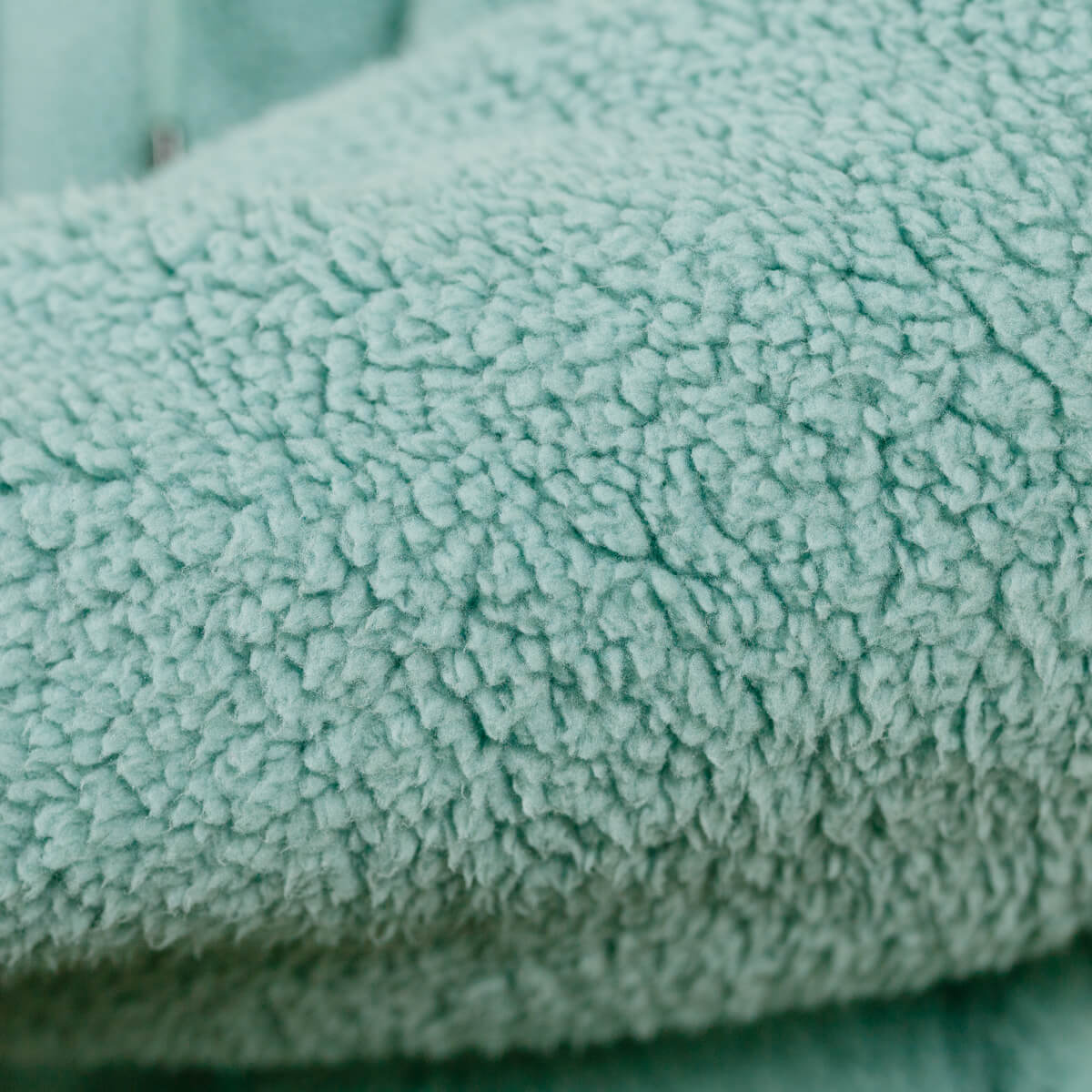 Close-up of sage green sherpa fabric texture on IV zip hoodie.
