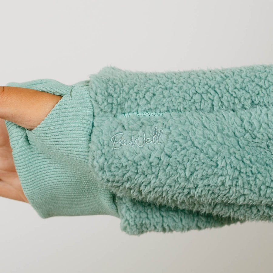 Person wearing seafoam color sherpa zip hoodie with ribbed cuff detail visible on arm.