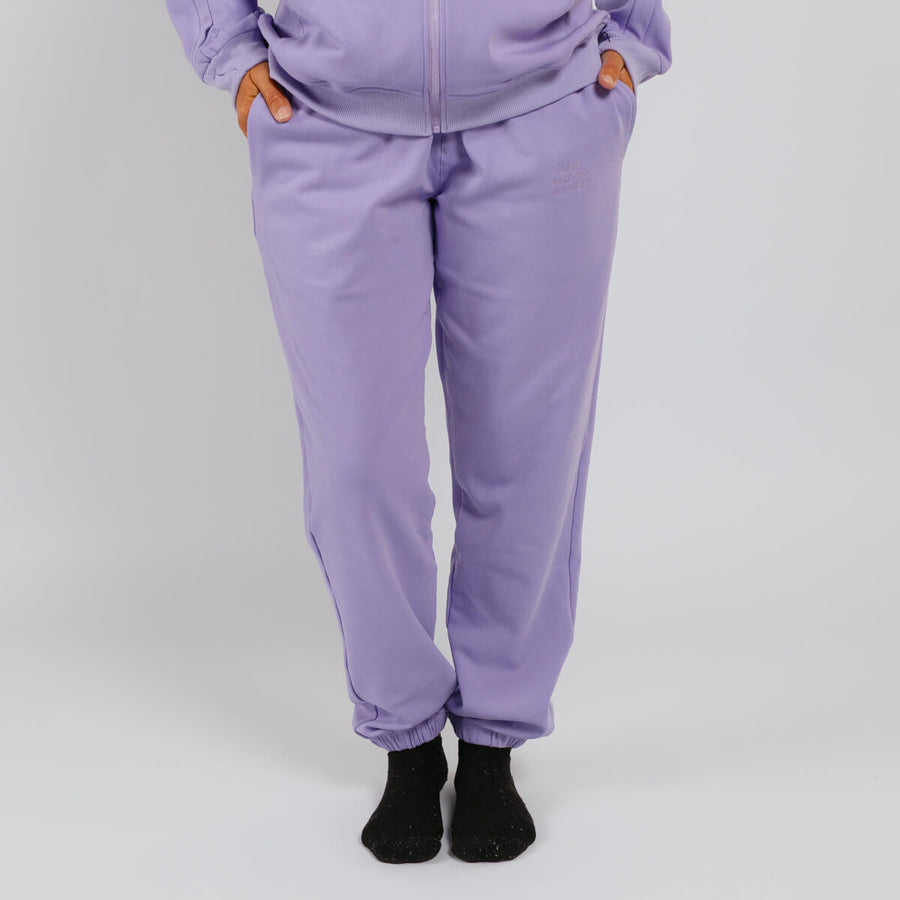 Person wearing lavender sweatpants with black socks against a white background.