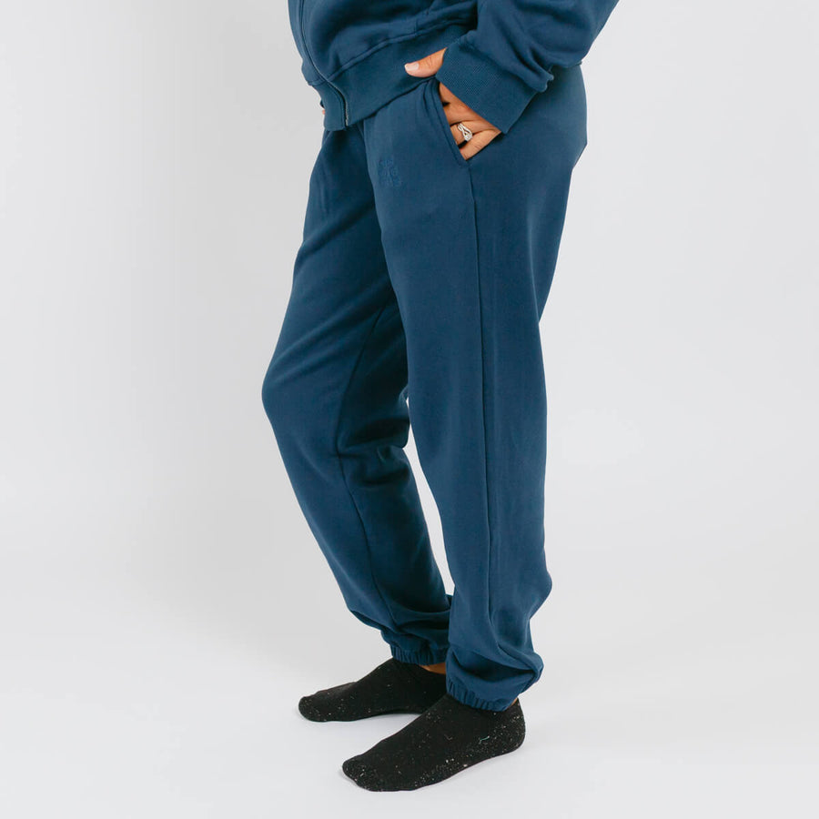 Navy blue sweatpants with orange pocket lining worn with black socks against a white background.