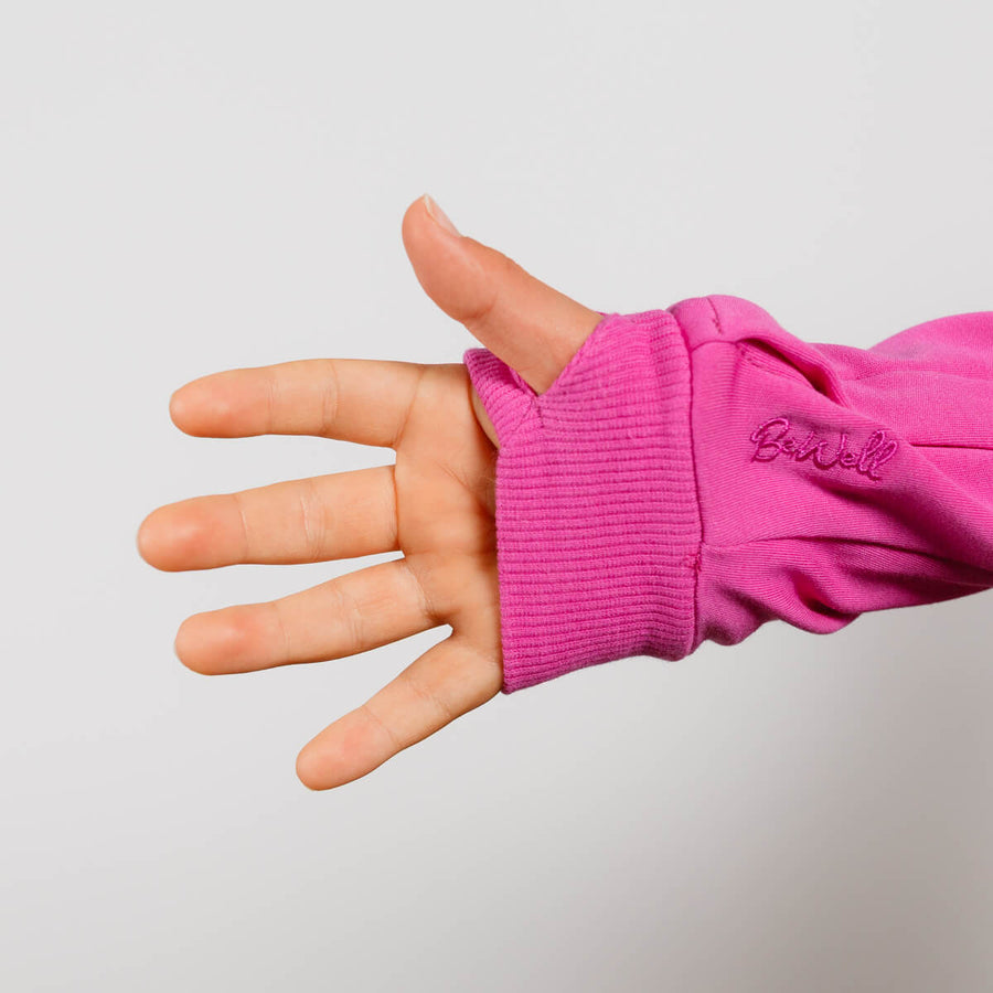 Child wearing hot pink IV zip hoodie with arm access zipper detail visible.