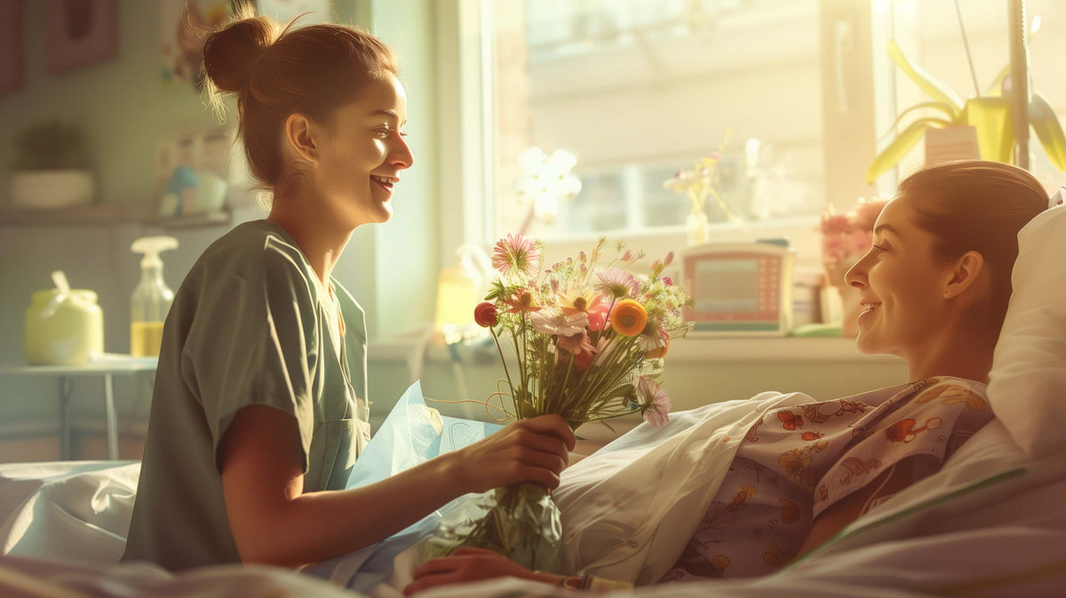 A healthcare worker presents flowers to a smiling patient resting in a hospital bed.