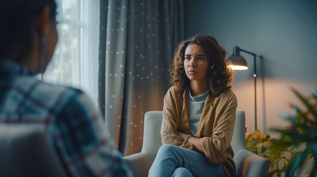 Two people sit facing each other in a thoughtful conversation, one appearing to listen intently while the other speaks.