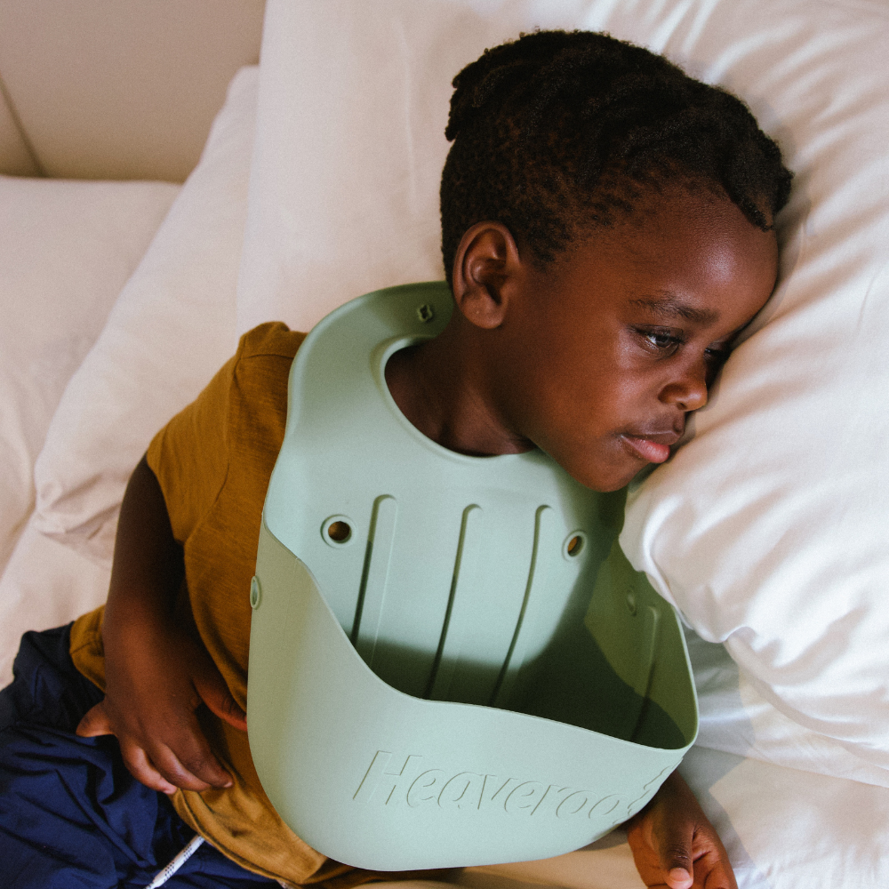 little boy in a bed wearing heaveroo bib