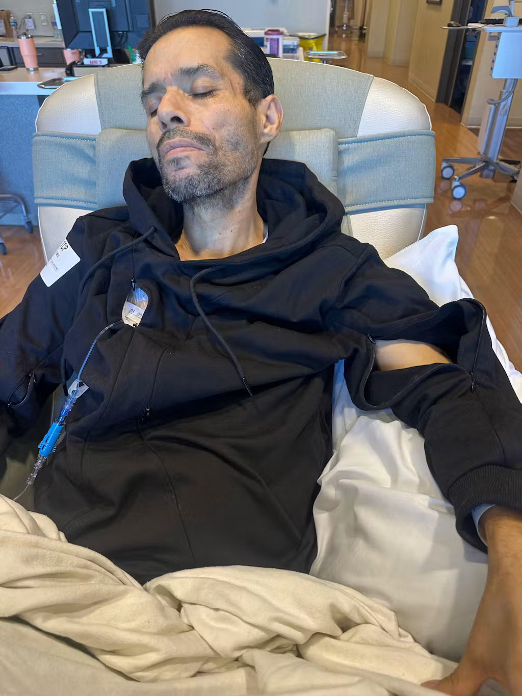 Andrea C.'s husband resting in his BeWell hoodie during treatment
