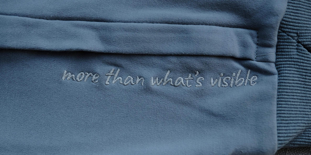 “more than what's visible” embroidered in silver thread down the hoodie sleeve