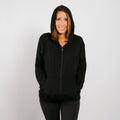 Woman wearing black bamboo IV zip hoodie with hood up, front view.
