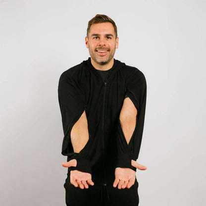 Man wearing a black hoodie with cut-out design on a plain background | Model is 5'8" 165lbs wearing size M