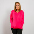 Woman wearing hot pink bamboo IV zip hoodie with front zipper, standing against white background.